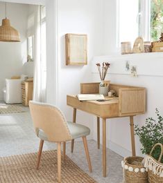 a room with a desk, chair and potted plant on the floor in it