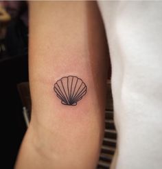 a small shell tattoo on the arm