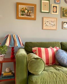 a green couch with colorful pillows and pictures on the wall