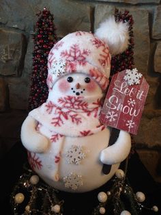 a snowman holding a sign that says let it snow on top of some christmas decorations