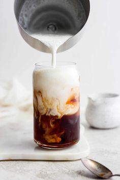 a pitcher pouring liquid into a glass filled with ice