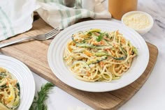 a plate of pasta with zucchini and parsley on a cutting board next to other dishes