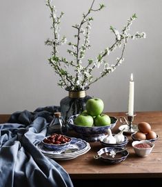 an arrangement of food on a table with flowers in a vase and candlesticks