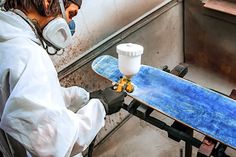 a man is working on a skateboard in a factory with protective gear and gas masks