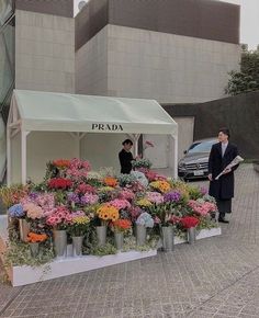 two people standing in front of a flower stand