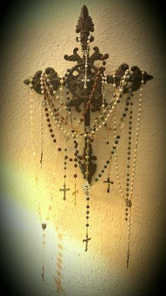 a chandelier with beads and crosses hanging from it's side on a wall