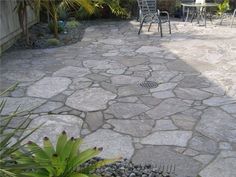 a stone patio with chairs and table in the background