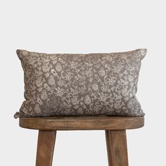 a brown and white pillow sitting on top of a wooden stool