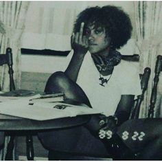 a black and white photo of a woman sitting at a table with her hand on her face