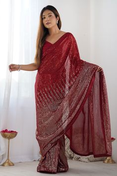 a woman in a red sari standing next to a window with her hands on her hips