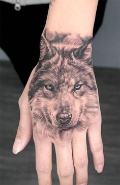 a hand with a wolf tattoo on it