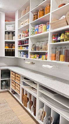 a kitchen with white cabinets and lots of shelves filled with food items on top of them