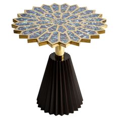 a gold and blue decorative object sitting on top of a black stand with an intricate design