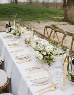 a long table set up with place settings and goldware for dinner guests to enjoy