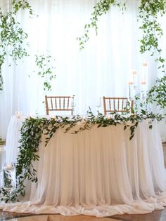 the table is decorated with greenery and candles for an elegant wedding reception in white