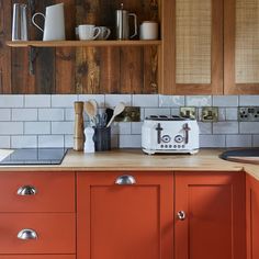 an orange kitchen with wooden cabinets and white tile backsplash, coffee maker on the counter