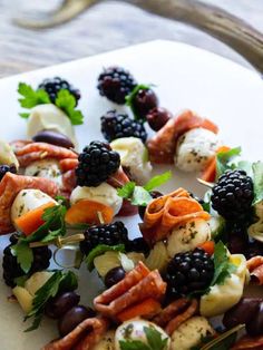 a white plate topped with blackberries and veggies on skewered skewers