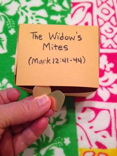 a hand holding a piece of paper with the words the widow's mites marked on it