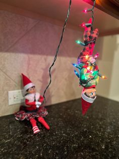 two elfs hanging from the ceiling with christmas lights