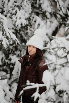 a woman standing in front of snow covered trees