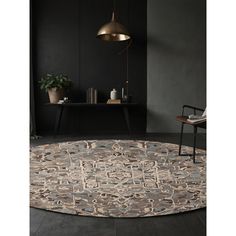 a round rug with an abstract design in grey and beige colors on a black floor