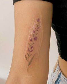 a woman's arm with a tattoo on it that has purple flowers in it