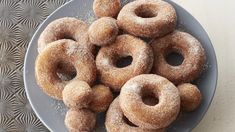 a plate full of sugared donuts on a table