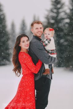 a man and woman holding a baby in the snow