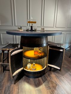 a round table with three bottles on it and two stools around the table in front of it