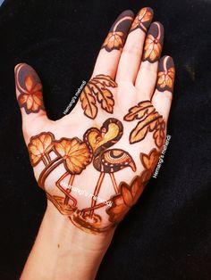 a person's hand painted with flowers and flamingos on the palm, which is decorated with leaves