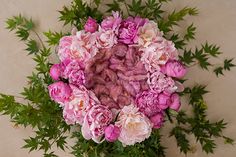 a bouquet of pink flowers sitting on top of a white countertop next to green leaves