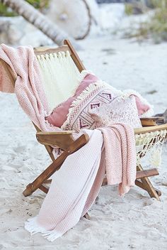 a hammock with blankets and pillows on the beach