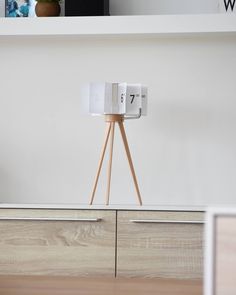 an alarm clock sitting on top of a wooden stand in front of a white wall