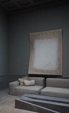 a couch and ottoman in a room with a large painting on the wall behind it