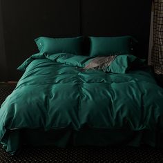 a bed with green sheets and pillows in a dark room