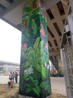 a painting on the side of a building with people standing around it and some buildings in the background