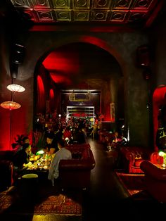 a dimly lit room with red lighting and lots of people sitting at tables in it