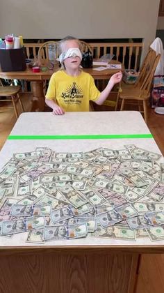 a young boy sitting at a table covered in money