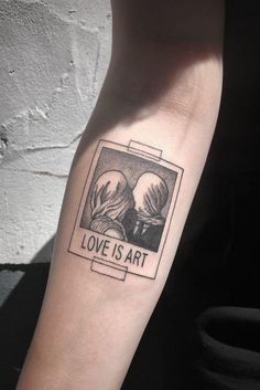 a person with a tattoo on their arm that reads love is art and the image of two people holding each other