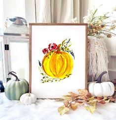 a painting of a pumpkin with flowers and leaves on the table next to other fall decorations