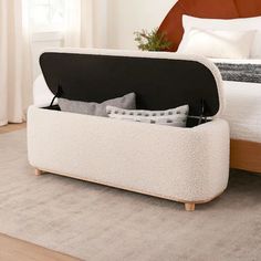 a bed with a storage compartment on top of it next to a rug and window