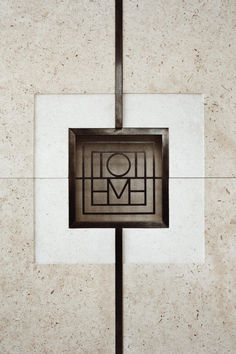 a square metal object with a heart in the center on a white tile wall behind it