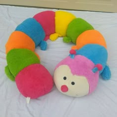 a very cute stuffed animal laying on a bed with a toy caterpillar attached to it's back