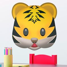 a yellow tiger head with black stripes on it's face and some colored pencils