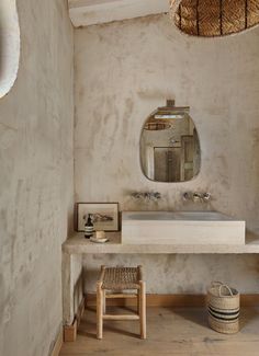 a bathroom with a sink, mirror and stool in the corner next to a wall