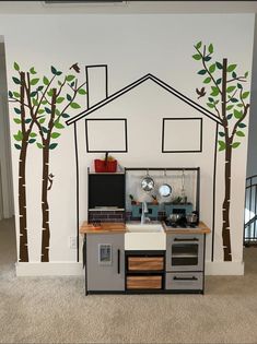 a kitchen area with an oven, microwave and tree decals on the wall behind it