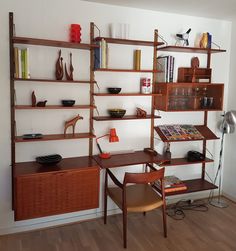 a room with some shelves and chairs on the wall next to a desk, bookshelf and lamp