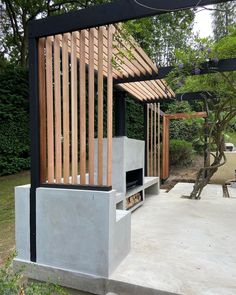 an outdoor fireplace in the middle of a concrete patio with wood slats on it