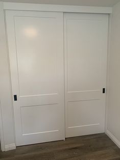 an empty room with two white doors and wood flooring on either side of the door