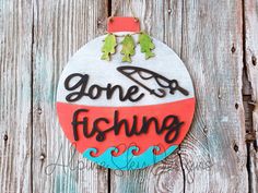 a painted ornament that says gone fishing on it, hanging on a wooden fence